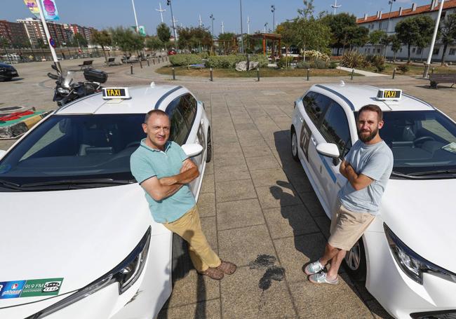 Juan y Adrián, apoyados en sus taxis en el Barrio Pesquero. Los dos coches son el mismo modelo.