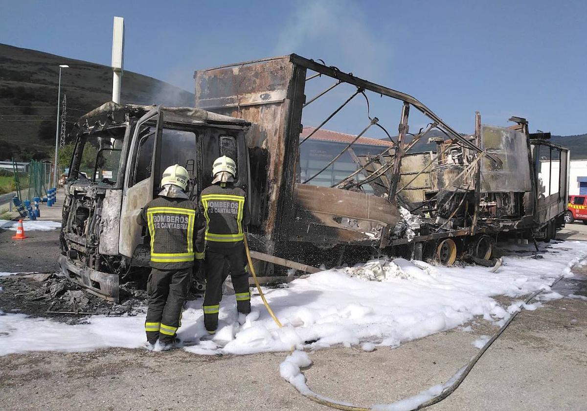 Dos bomberos arrojan espuma sobre los restos del camión para evitar que se reavivara el fuego.