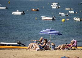 Tres mujeres toman el sol en la playa de los Peligros en Santander.