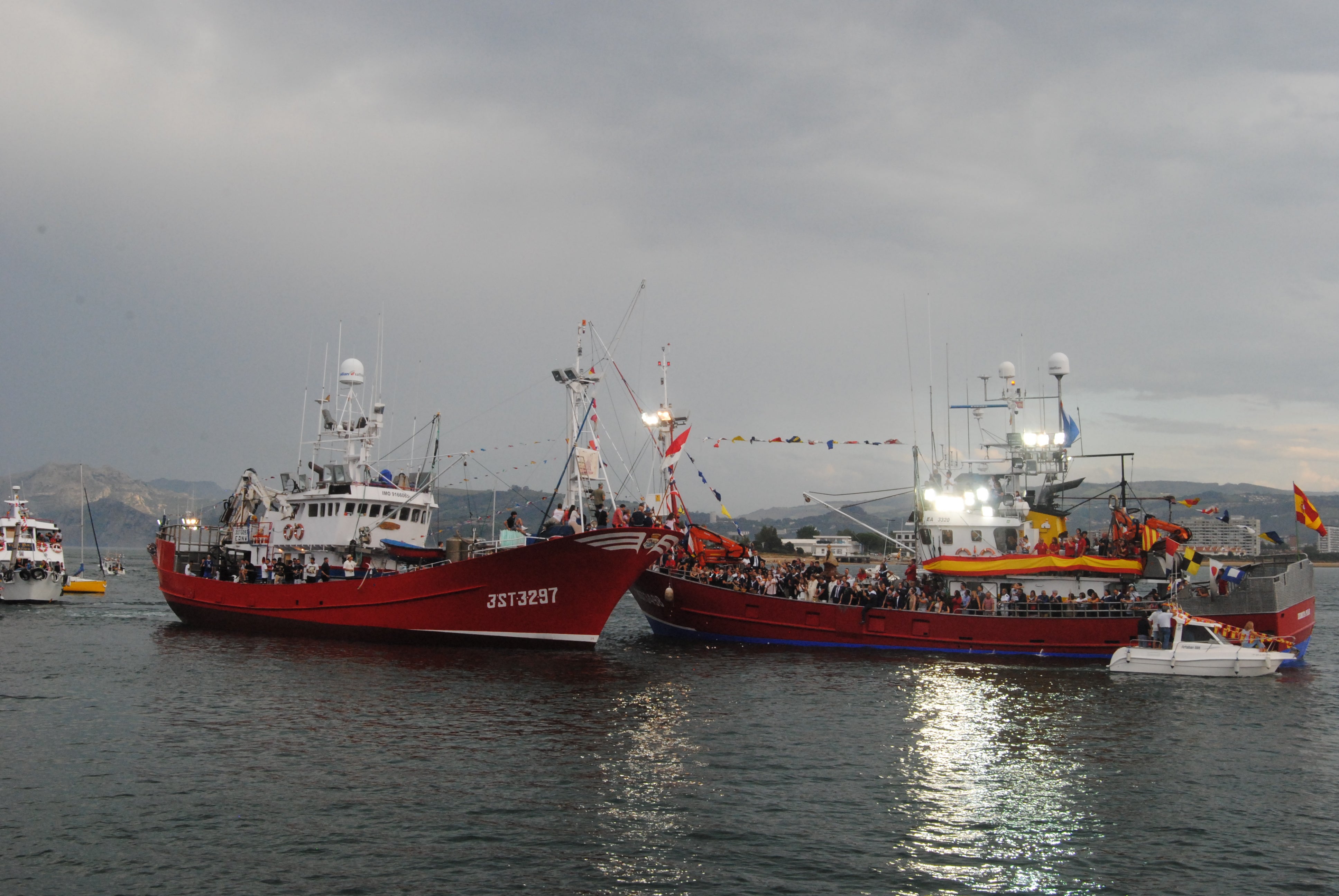 Las embarcaciones pasando delante del barco de la Morenuca para ser bendecidos por el párroco.