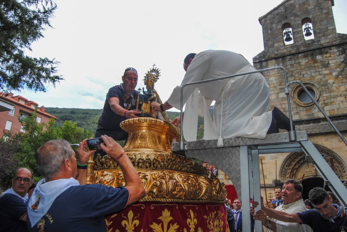 El integrante de la Archicofradía Virgen del Puerto, Edu Cabieces, coloca con la ayuda de un religioso, la talla en la carroza tras su salida de la iglesia 