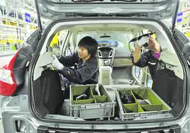 Operarios asiáticos instalando componentes en una fábrica de automóviles en la ciudad china de Chongqing.
