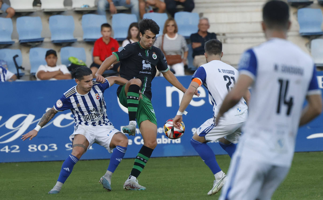 Marcos Bustillo busca el control del balón ante la presión de dos futbolistas gimnásticos. 