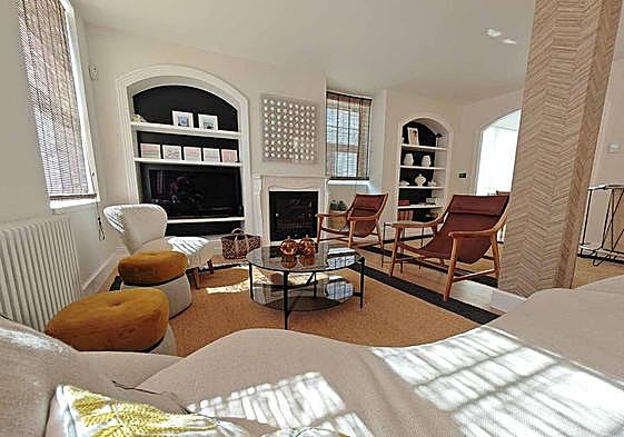 Vista completa del salón, con el sofá curvo y la barra al fondo, a la derecha, pegada al arco que da paso al comedor.