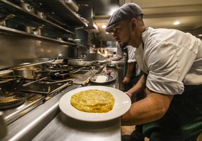 Un miembro del equipo de cocina emplata una de las decenas de tortillas que cada día se preparan en Cañadío Santander.