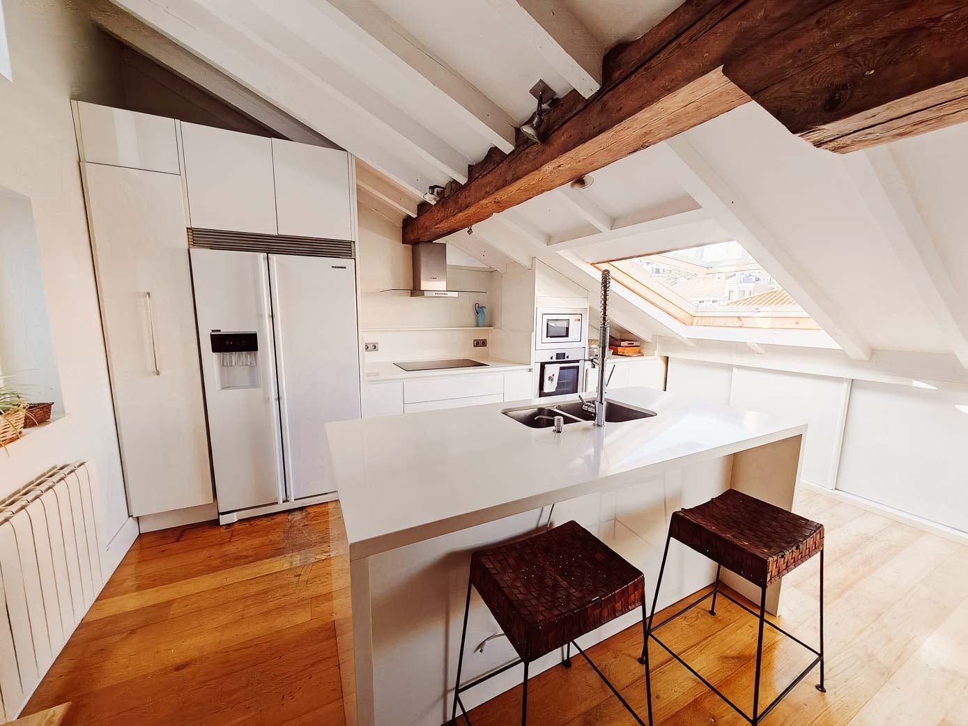 Zona de la cocina diseñada por Manolo Gestera, con muebles modernos e isla de Silestone, en blanco.