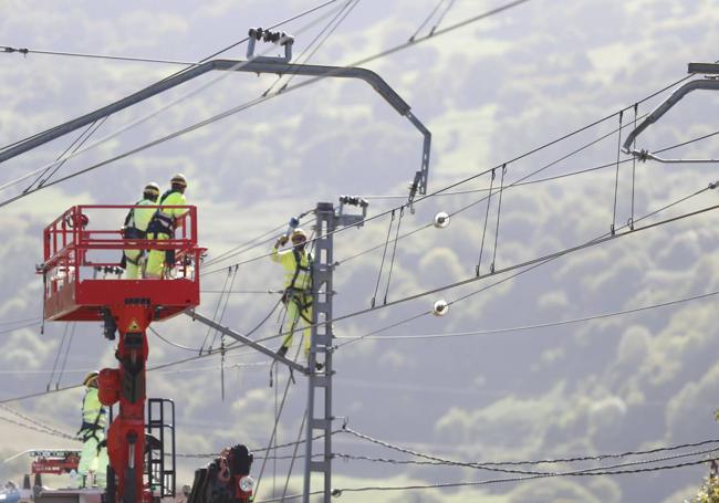 Los operarios quitan los cables para que la grúa pueda pasar.
