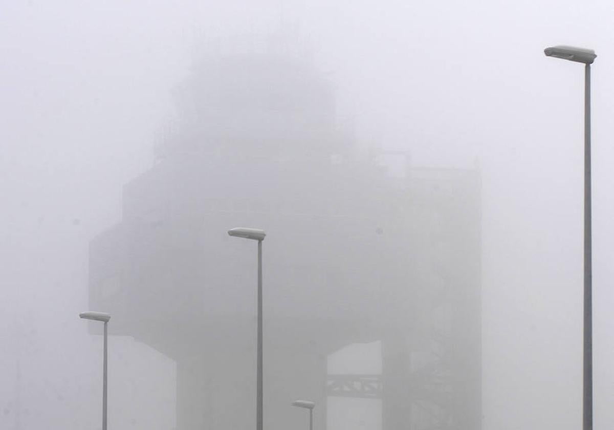 Detalle de la torre de control del Seve Ballesteros cubierta por una densa niebla.