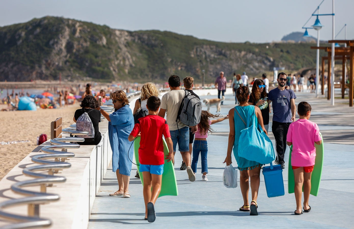 Paseantes junto a la playa de La Concha en Suances