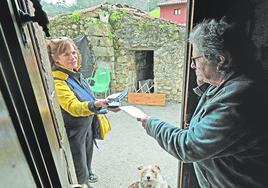 Una cartera rural entrega una carta a una vecina en su casa.