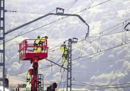 Varios operarios retiran la catenaria para que una grúa pudiera acceder al descarrilamiento de Lantueno.