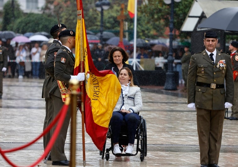 Una mujer en silla de ruedas se dispone a besar la bandera nacional.