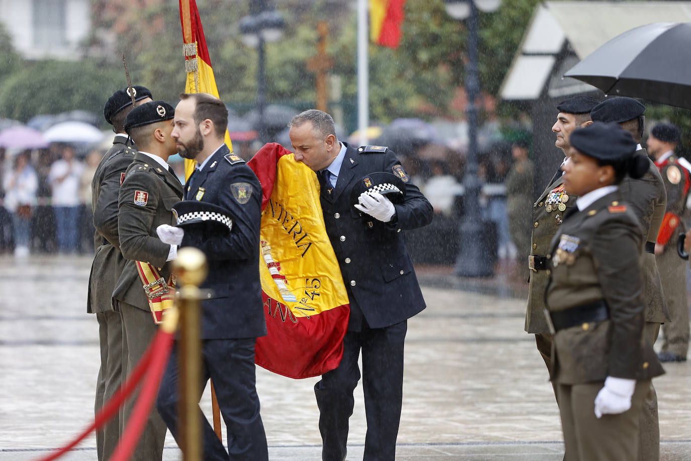 Un agente de la Policía Local besa la bandera nacional.