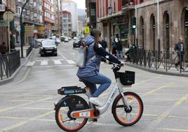 Una joven cruza Cuatro Caminos con una bicicleta eléctrica.