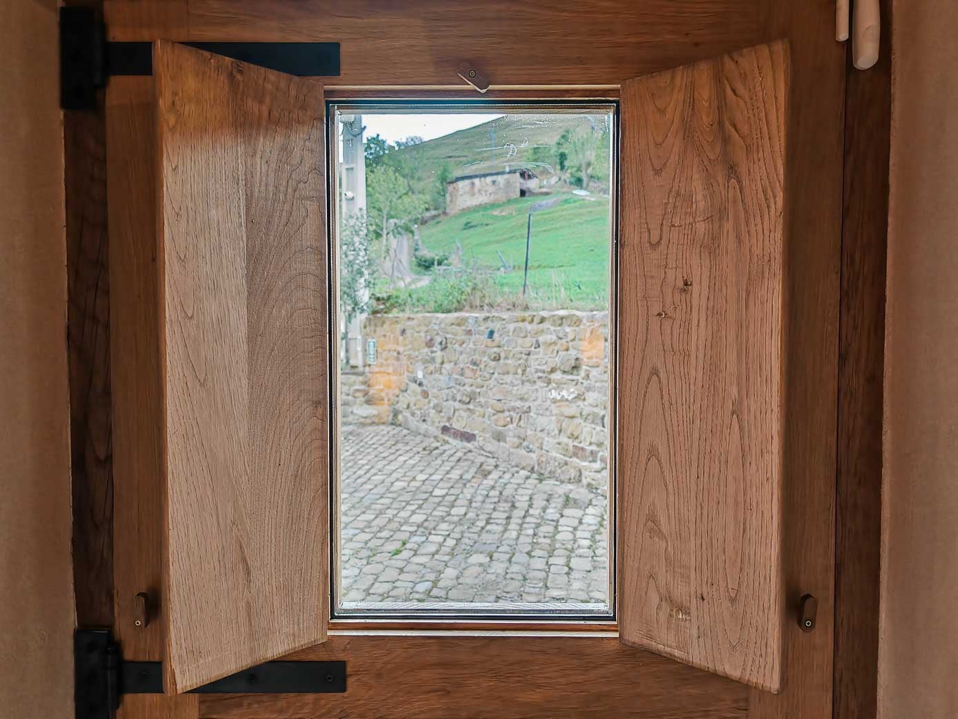 Vista desde el ventanuco de la puerta de una de las habitaciones al patio común de las cabañas.