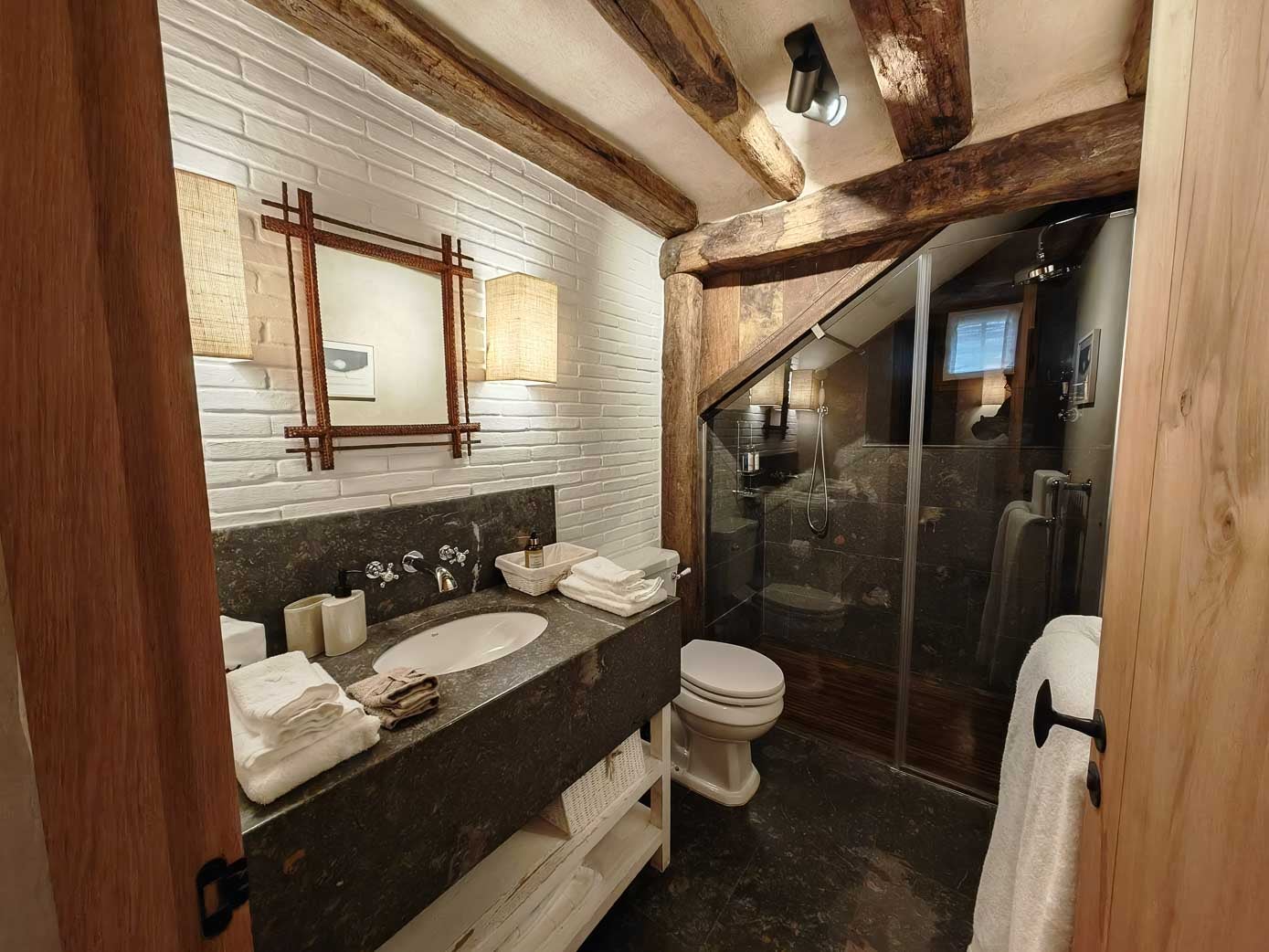 Baño con ducha, cuyo interior está forrado en madera de iroco.