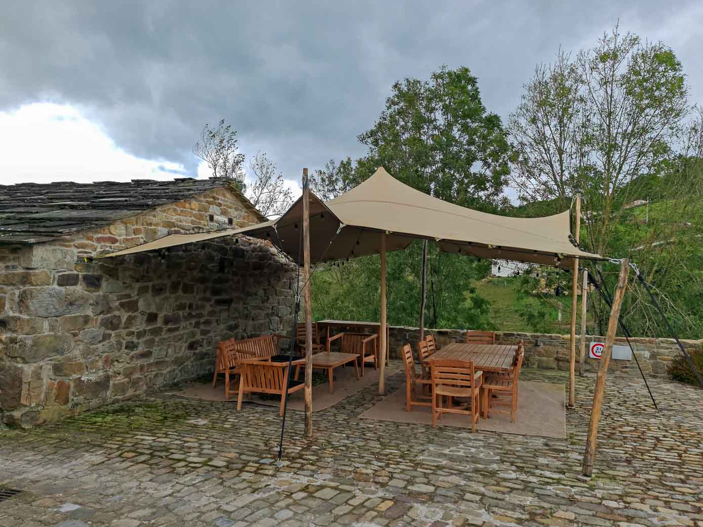 Comedor de verano, bajo una carpa, de la que cuelgan varias tiras de bombillas, para los huéspedes de Cabañas Pax.