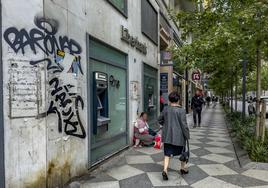 Un grafiti en la fachada de una sucursal de Liberbank cerrada preside un tramo de la calle Isabel II.