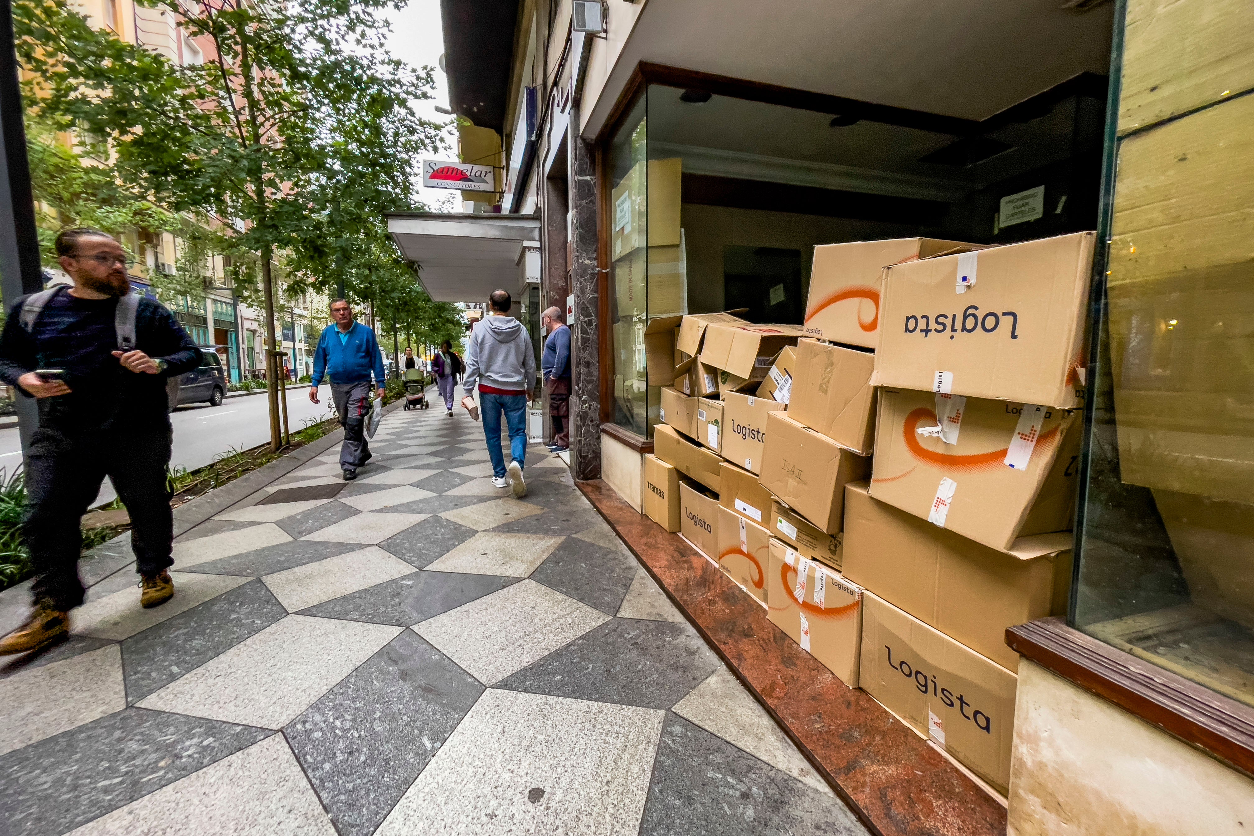 Varios vecinos pasean por la calle Isabel II y observan las cajas de cartón en uno de los locales vacíos de la zona.