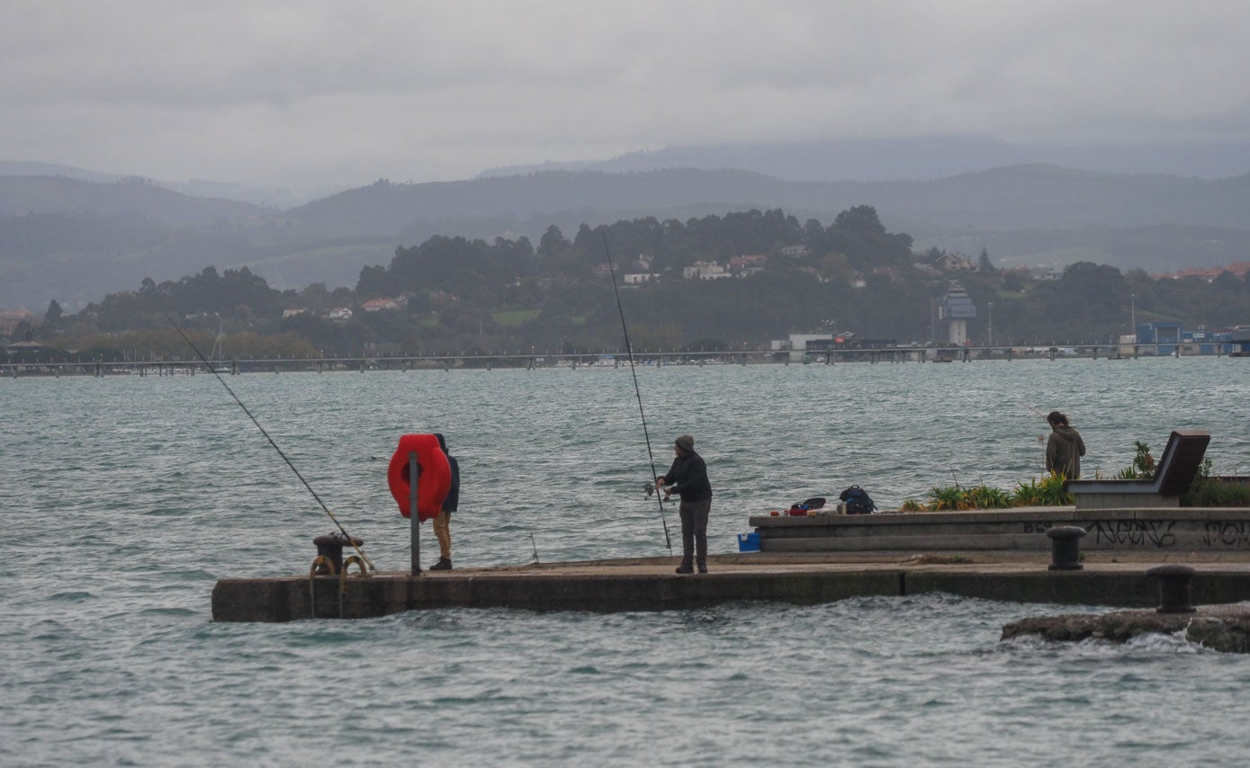 Unos aficionados a la pesca lanzan la caña durante la pleamar.