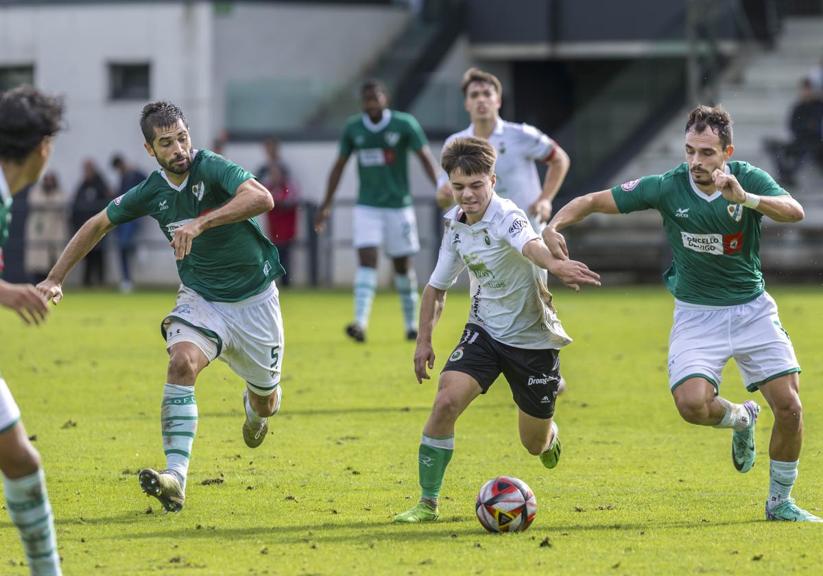 Neco Celorio conduce el balón entre dos rivales.