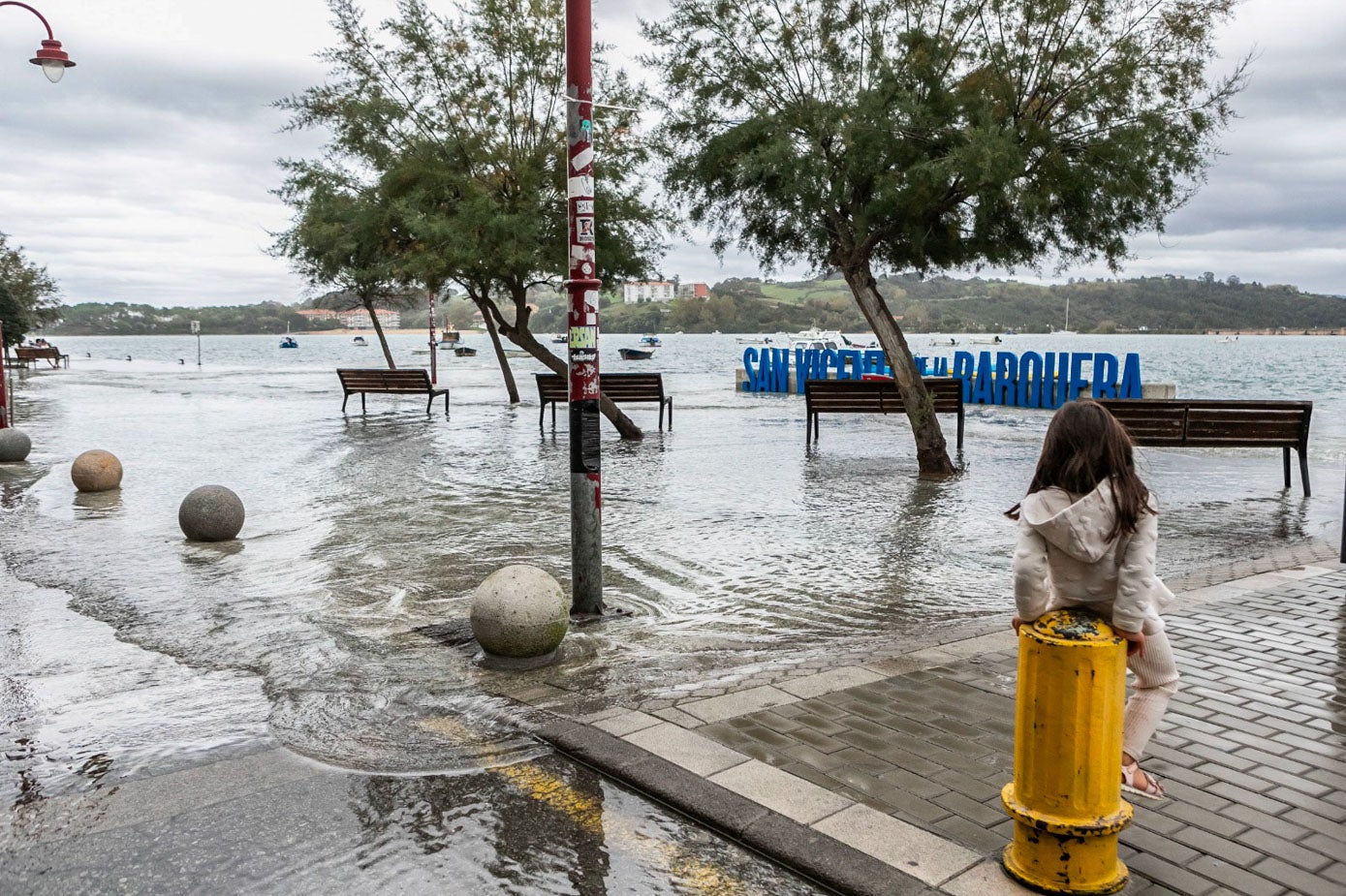 Una niña desde lo alto de un bolardo contempla la llegada del agua