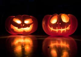 Dos calabazas naturaleza vaciadas y con una vela dentro.