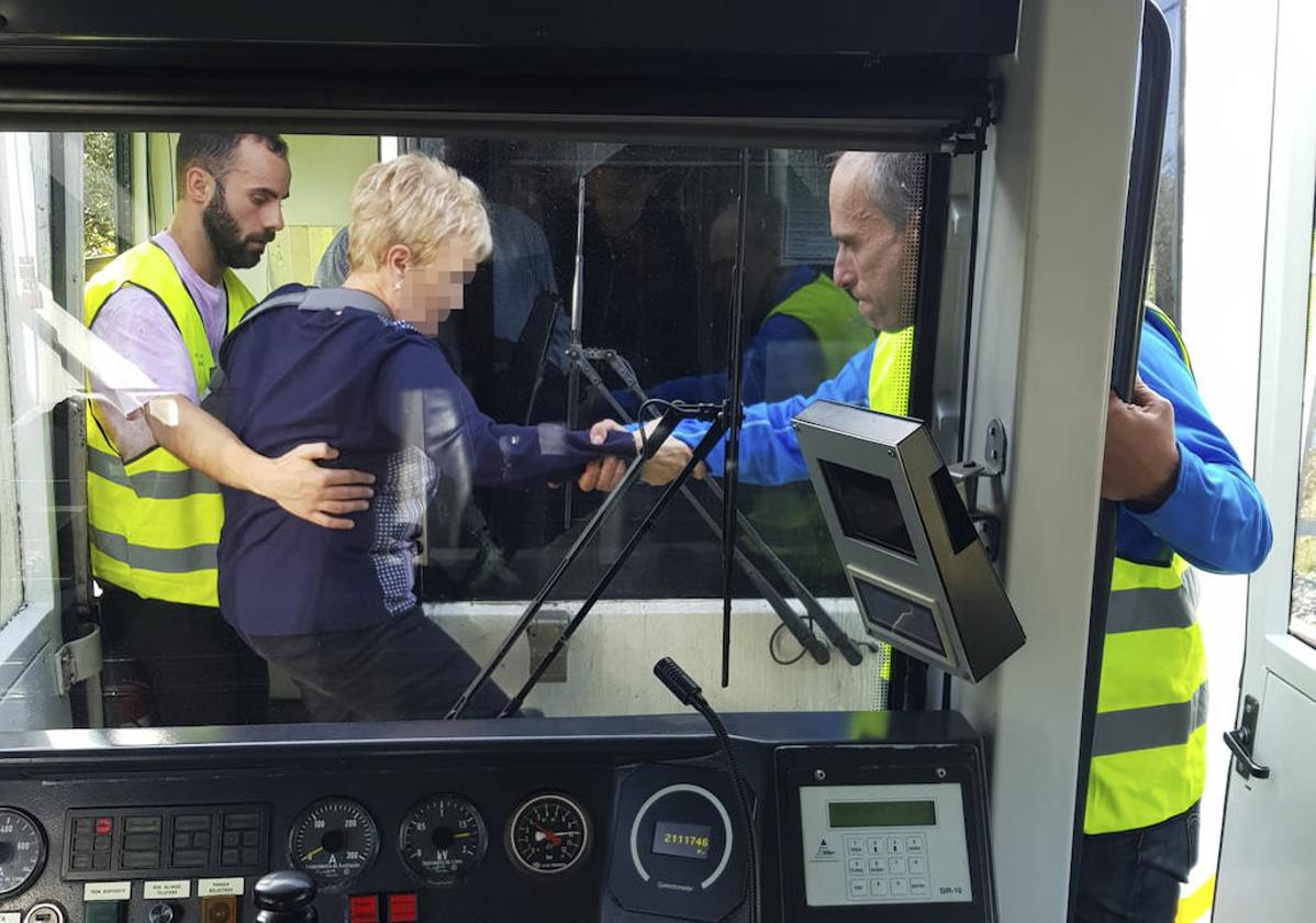 Dos operarios de Renfe ayudan a una mujer a pasar de un convoy a otro.