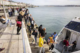 Vecinos y turistas se suben este martes a una lancha de los Reginas en la bahía de Santander cuando el agua estaba aún en calma.