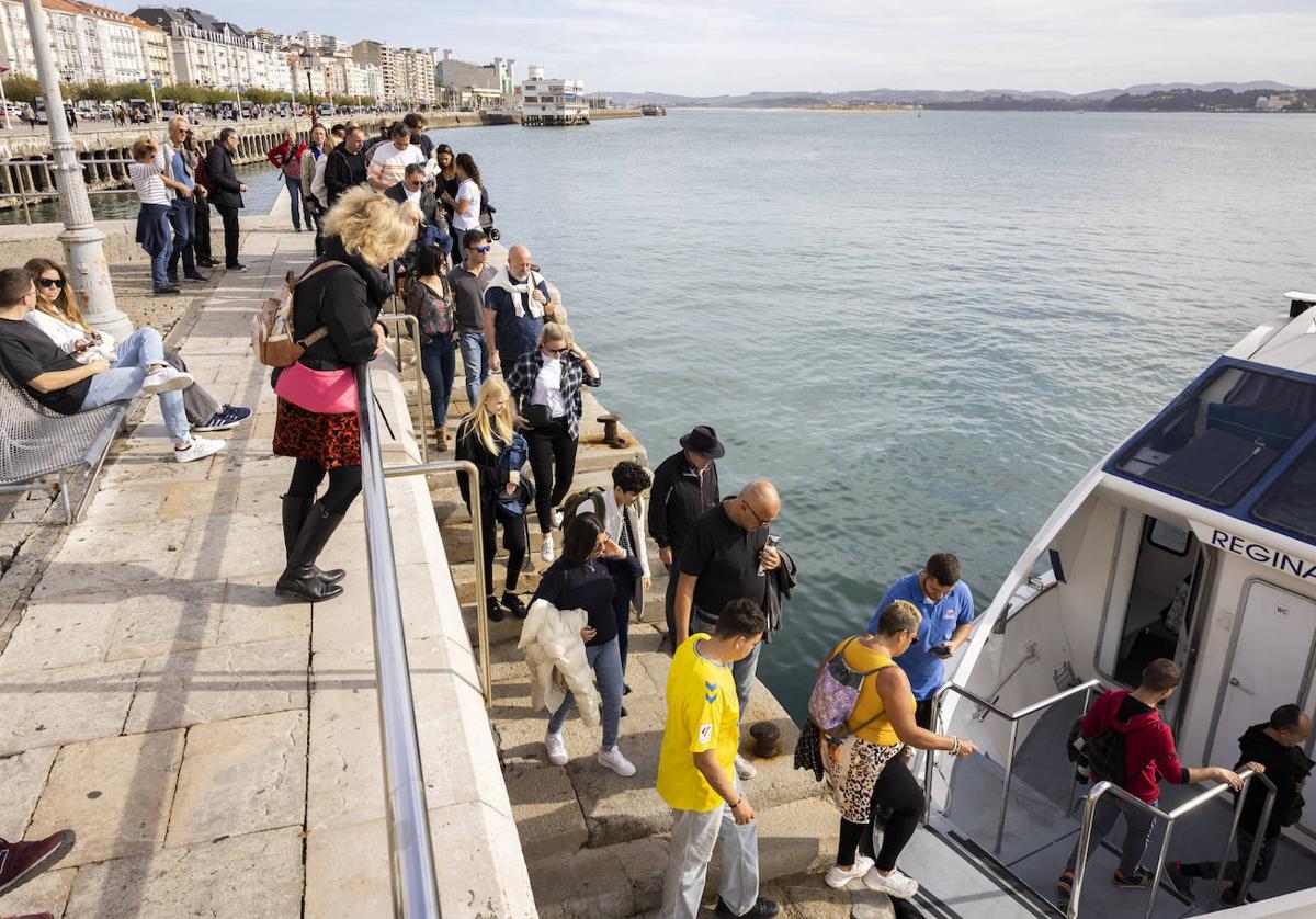 Vecinos y turistas se suben este martes a una lancha de los Reginas en la bahía de Santander cuando el agua estaba aún en calma.