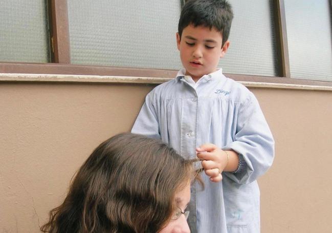 Diego Lainz, con seis años, en el patio del colegio peinando a una profesora.