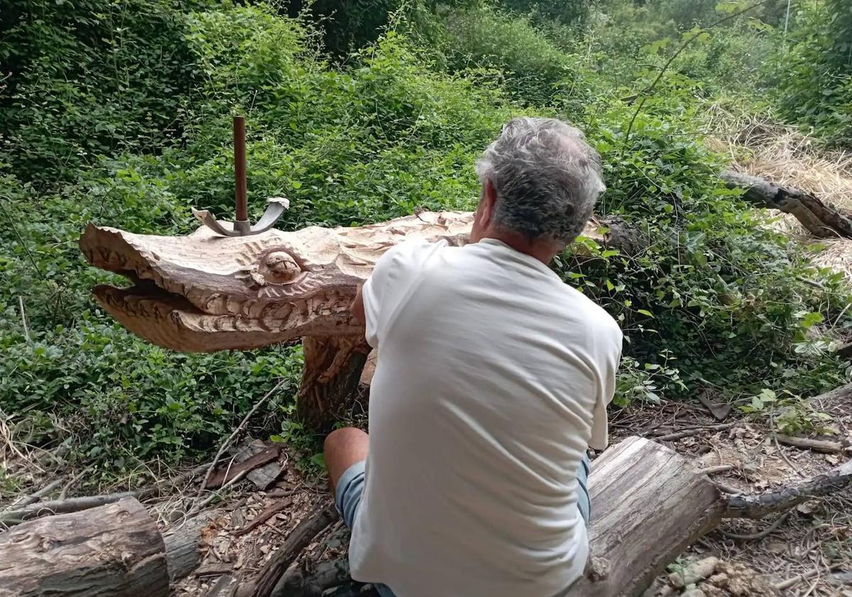 Imagen principal - Arriba, el autor de las tallas trabajando antes de los destrozos en una de las figuras de espaldas para conservar el anonimato. Abajo, dos de sus trabajos realizados con los troncos caídos.