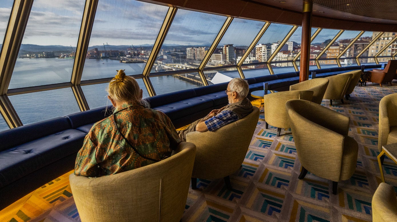 Dos pasajeros disfrutan de las vistas de la bahía desde el barco de lujo.