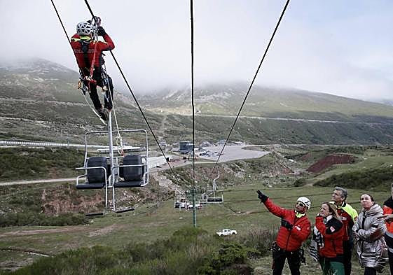 Uno de los rescatadores avanza por los cables del telesilla y otro explica a la consejera Isabel Urrutia, al director de Cantur Luis Martínez y a la directora de la estación, Cristina López en que consiste el ejercicio.
