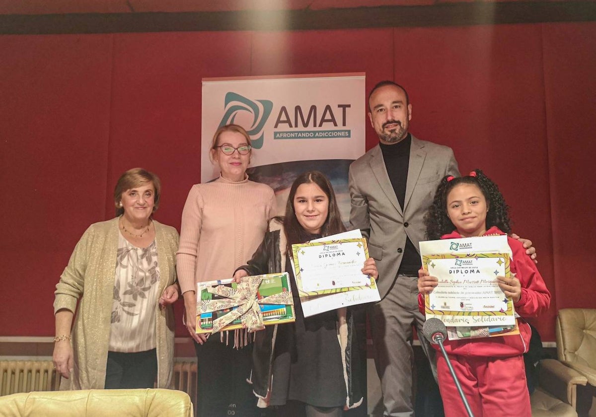 Escolares reciben un diploma de reconocimiento, tras participar en el diseño del calendario solidario de AMAT, este martes, junto a representantes de la asociación, del Ayuntamiento y del Gobierno regional.