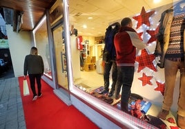 El propietario de una tienda de Cabezón prepara el escaparate para Navidad.