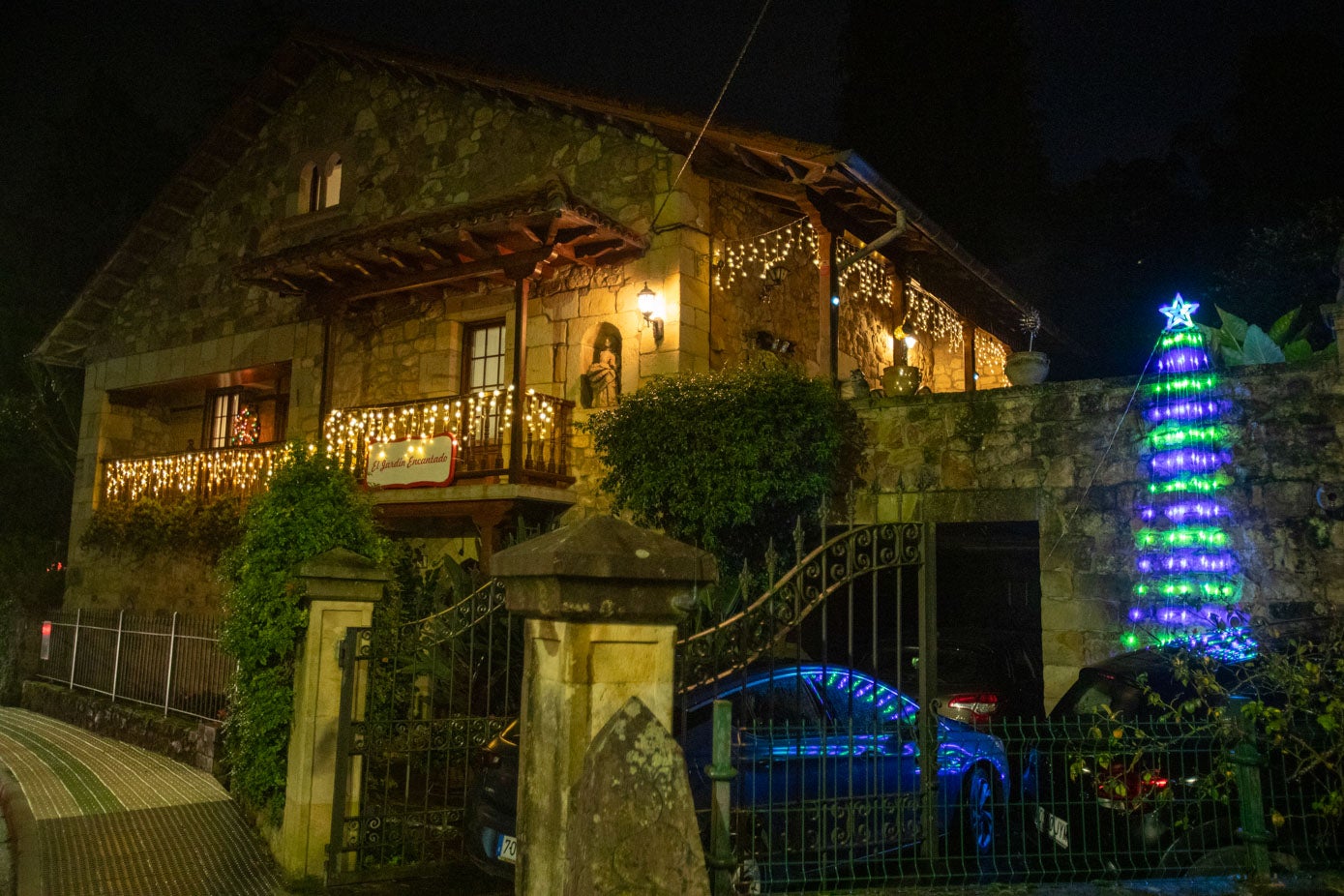 Balcones iluminados con guirnaldas y un árbol en otra de las casas.