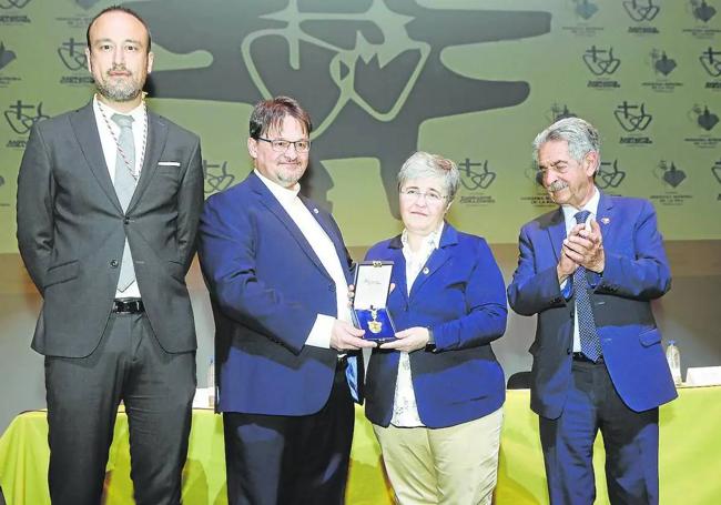 Aurelio Cayón, representante del colegio La Paz, y Nuria Arias, de los Sagrados Corazones, sostienen la Medalla de Oro, flanqueados por López Estrada y Revilla, este miércoles, en el Teatro Concha Espina.