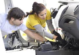 Un hombre y una mujer trabajan en el montaje de las piezas de un automóvil.