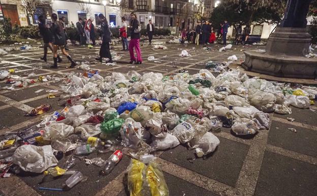 Los jóvenes más noctámbulos apuran las últimas horas de la Nochevieja, entre bolsas de basura y restos de botellón, en la Plaza de Pombo.