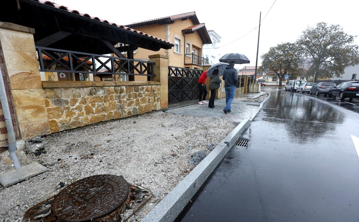 Varios vecinos caminan por una de las aceras sin terminar en el barrio de San Lorenzo. 