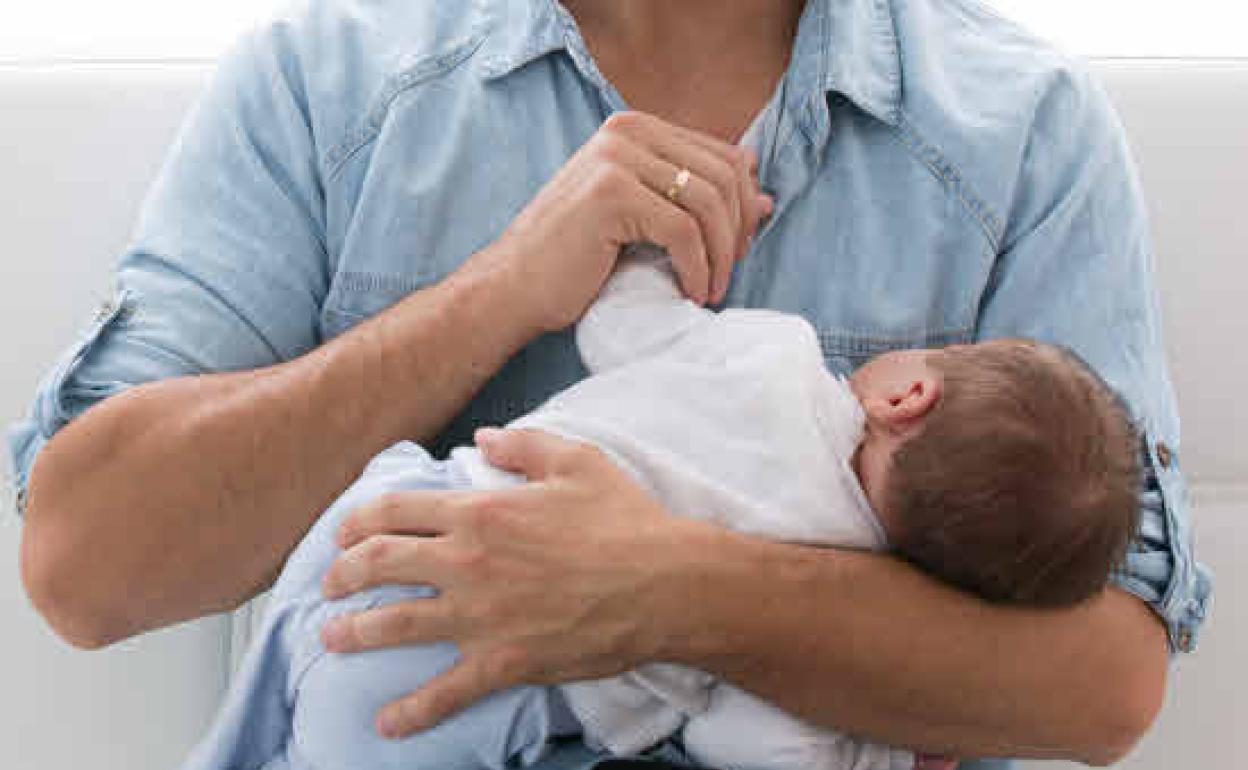 Imagen de archivo de un padre con un bebé recién nacido.