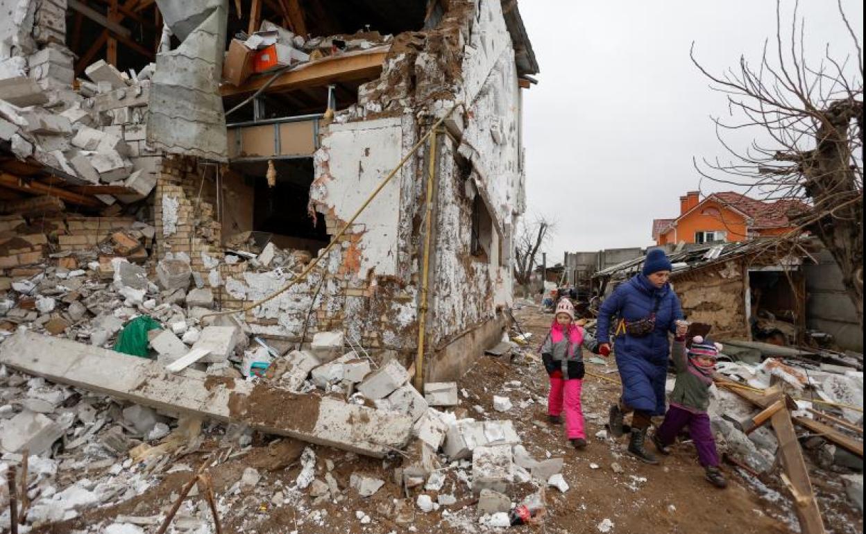 Una mujer camina con sus hijos a través de la destrucción provocada por un ataque aéreo ruso en Hlevakha, a las afueras de Kiev. 