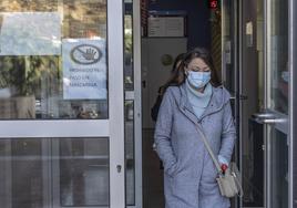 Una mujer abandona un centro de salud con la mascarilla puesta.