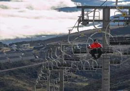 Un operario de Alto Campoo sube a la zona superior de la estación de esquí en el telesilla, sin apenas rastro de nieve en el horizonte.