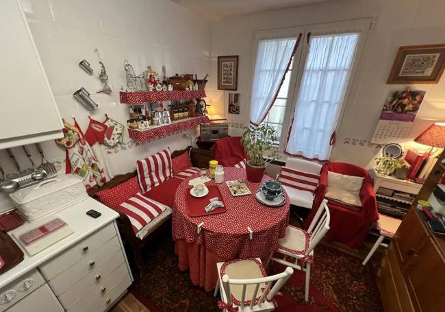 La cocina tiene muebles blancos y está decorada con textiles en tonos rojos.