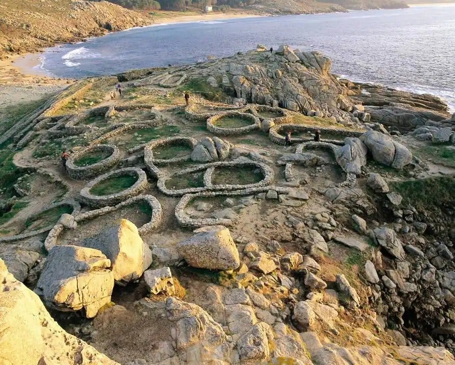 Los celtas eligieron este lugar como asentamiento por su belleza y ubicación estratégica. Desaparecieron, pero los restos del castro de Baroña han permanecido junto al mar ajenos al paso del tiempo. De aspecto salvaje y natural, hay que llegar hasta esta playa por un sendero de tierra. No hay servicios ni duchas, pero sin calma y una arena fina y blanca que es una delicia pisar con los pies descalzos. Las aguas son algo frías, sobre todo para los acostumbrados al Mediterráneo, pero a cambio dicen los entendidos que tienen tanto yodo que son perfectas para broncearse. Mejor sin traje de baño, que no por nada este fue uno de los escenarios míticos del primer nudismo patrio.