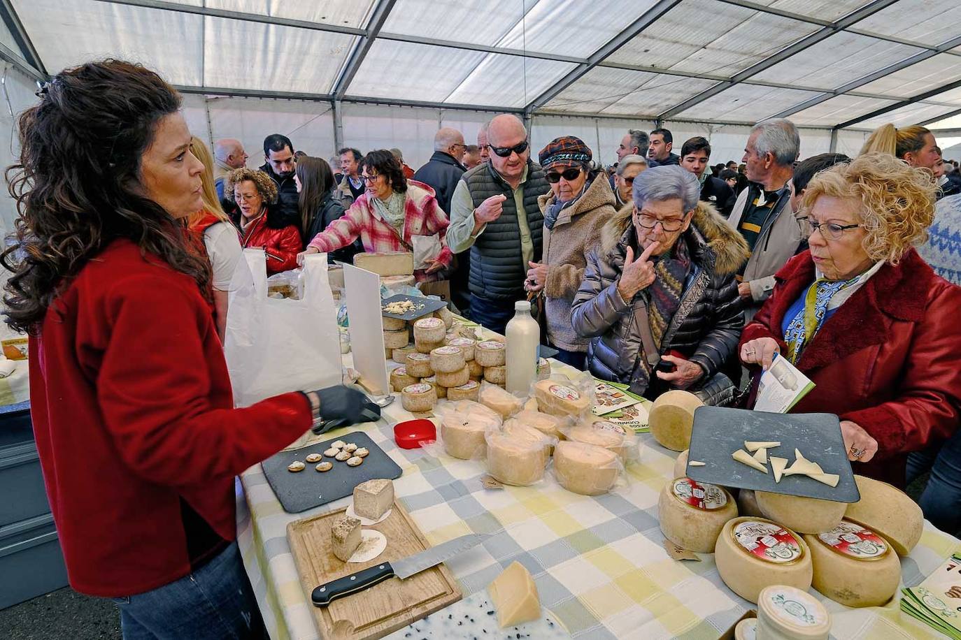 Una de las queseras da a probar a la gente queso de Cudaña