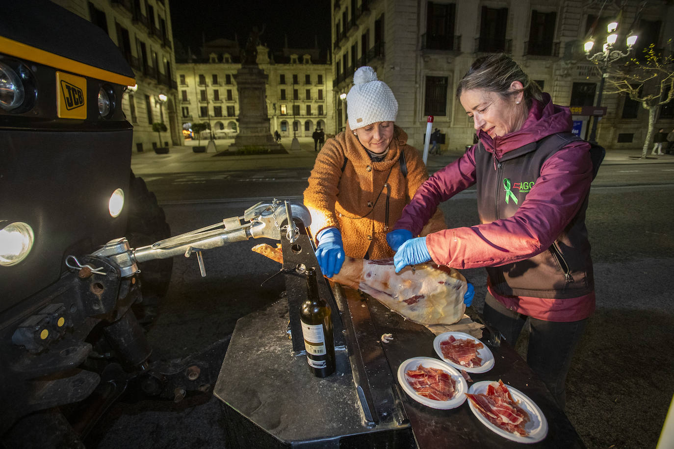 La exdiputada Marta García corta jamón para repartir entre los agricultores que decidieron pasar la noche en Santander.