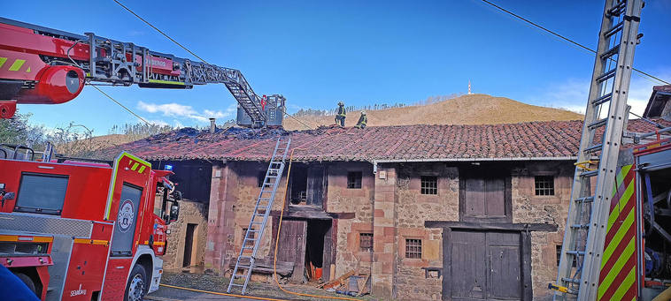 Bomberos trabajan en el desescombro de la vivienda tras apagar las llamas.